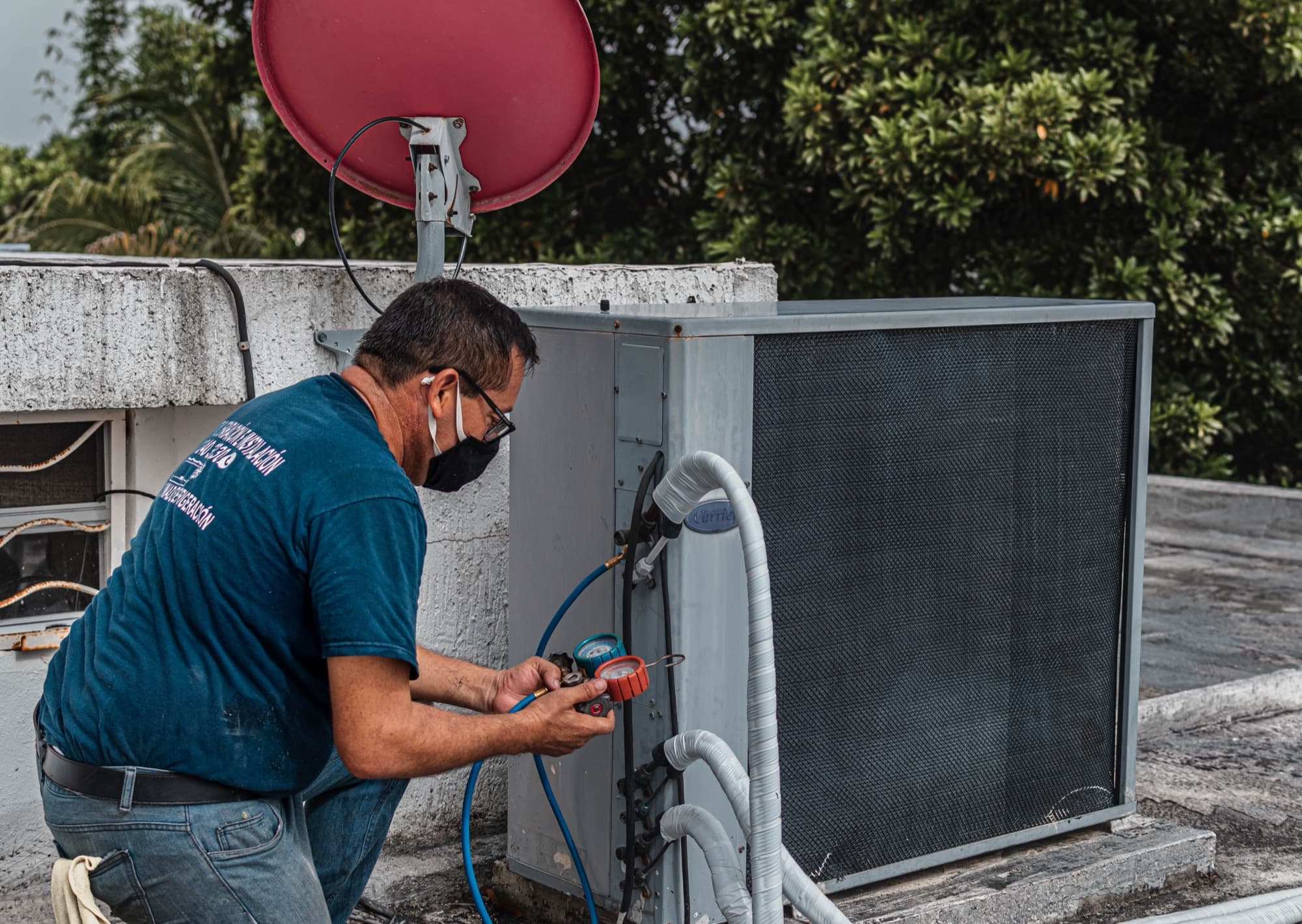 Technician checking refrigerant gauges on a rooftop air conditioner