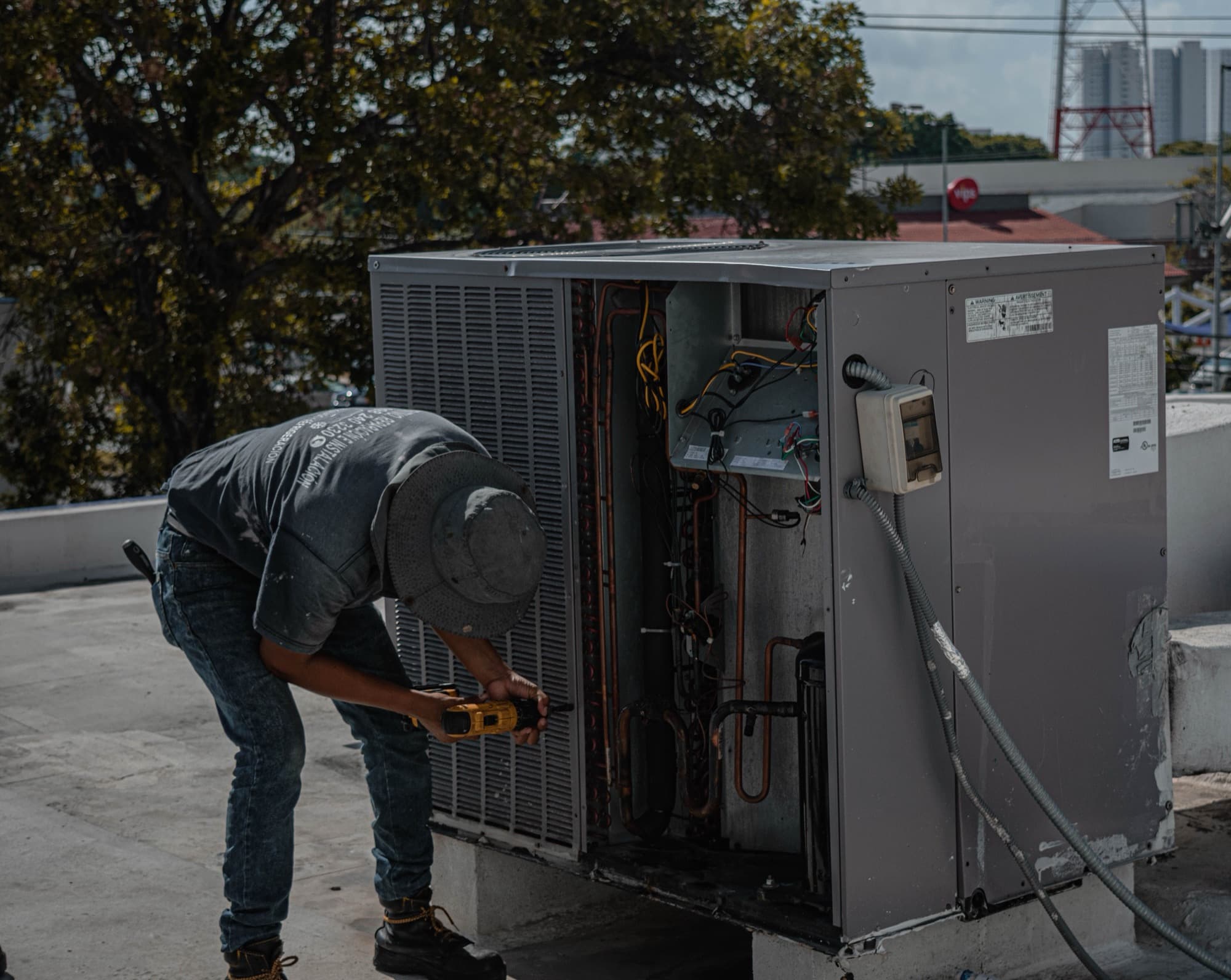 Technician working inside an open rooftop air conditioner