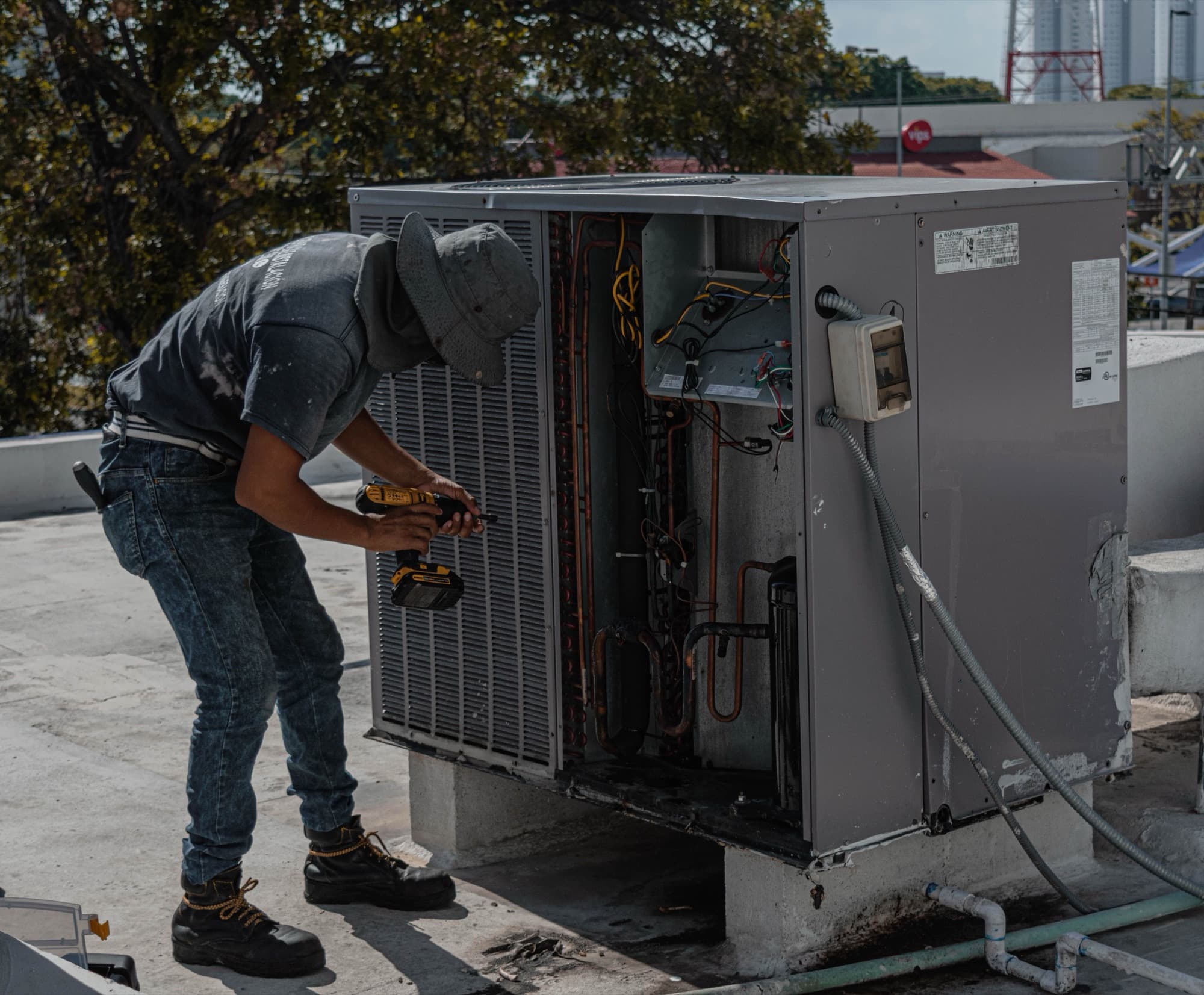 Technician repairing an open rooftop air conditioner