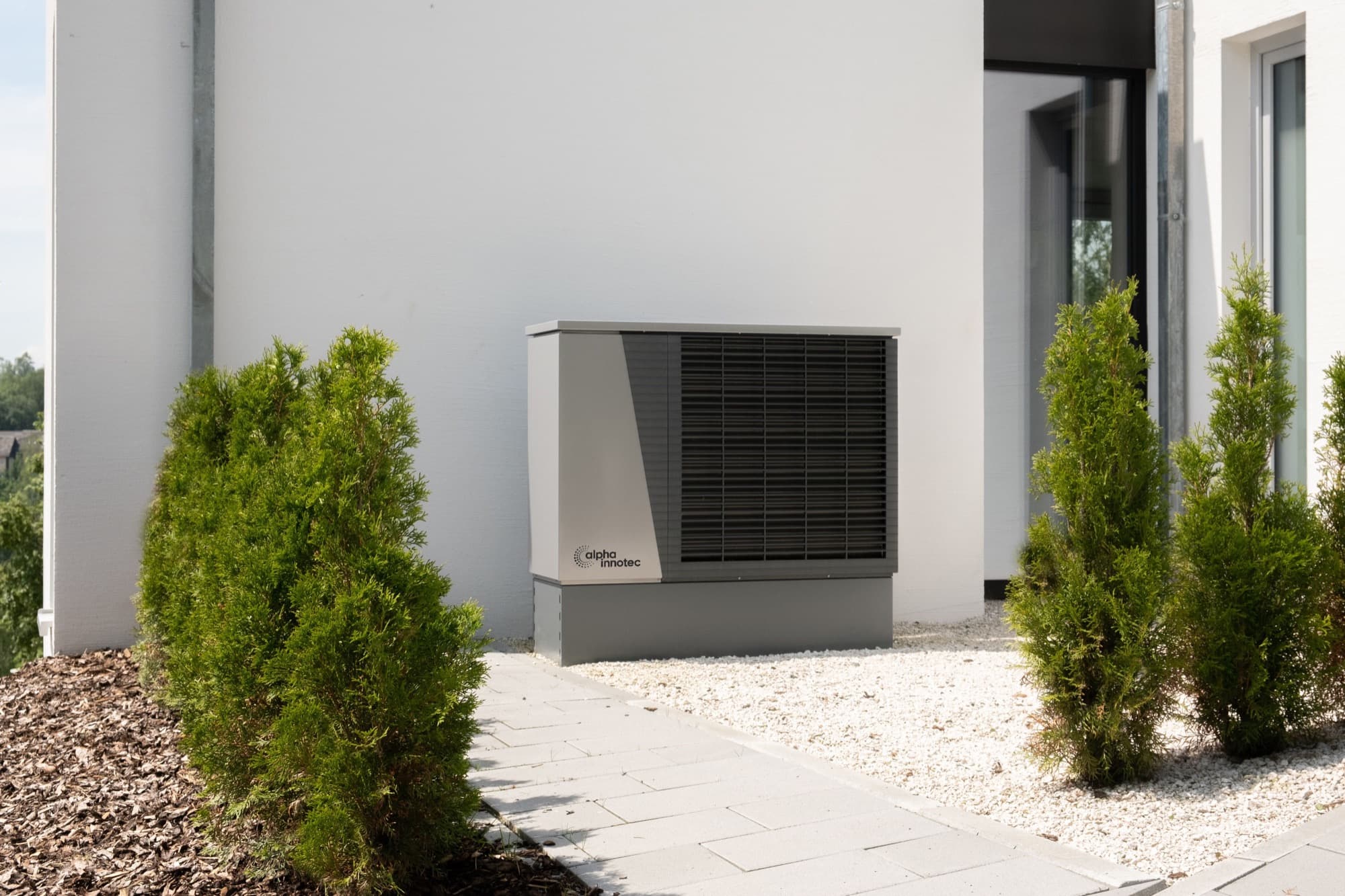 Outdoor air conditioner mounted beside a garden wall